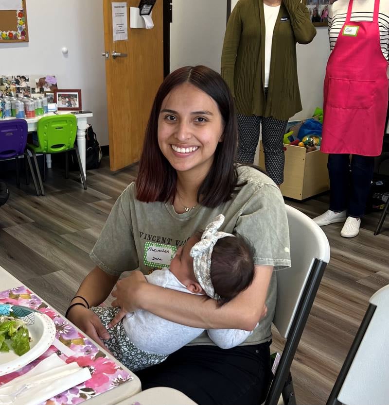 Salesperson with couple buying baby clothes in shop